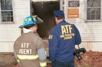Photograph of two firemen preparing to enter a burned building.