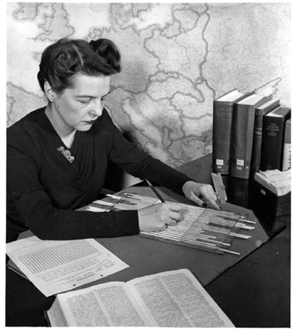 A historical photo of an examiner in the Cryptanalysis Section using alphabet strips to solve a clandestine cipher message