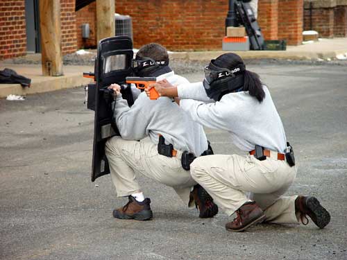 Two cadets behind a ballistics shield